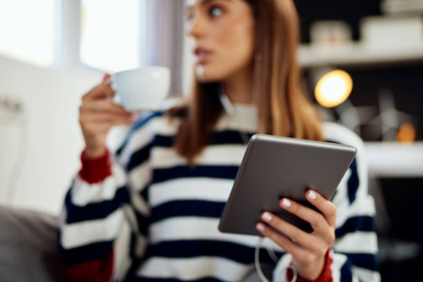 istock Woman drinking coffee and using tablet while sitting in bedroom. 1188409827