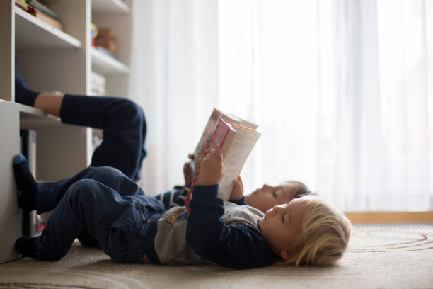 Cute child, boy, reading a book at home, happy to learn