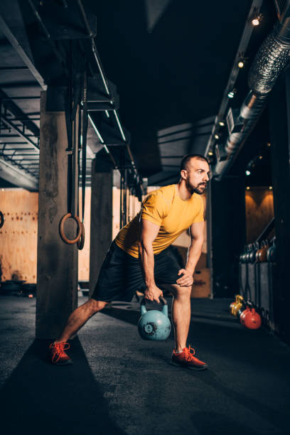 istock Muscular sporty young man doing a kettlebell lunge exercise in a gym 1188417377