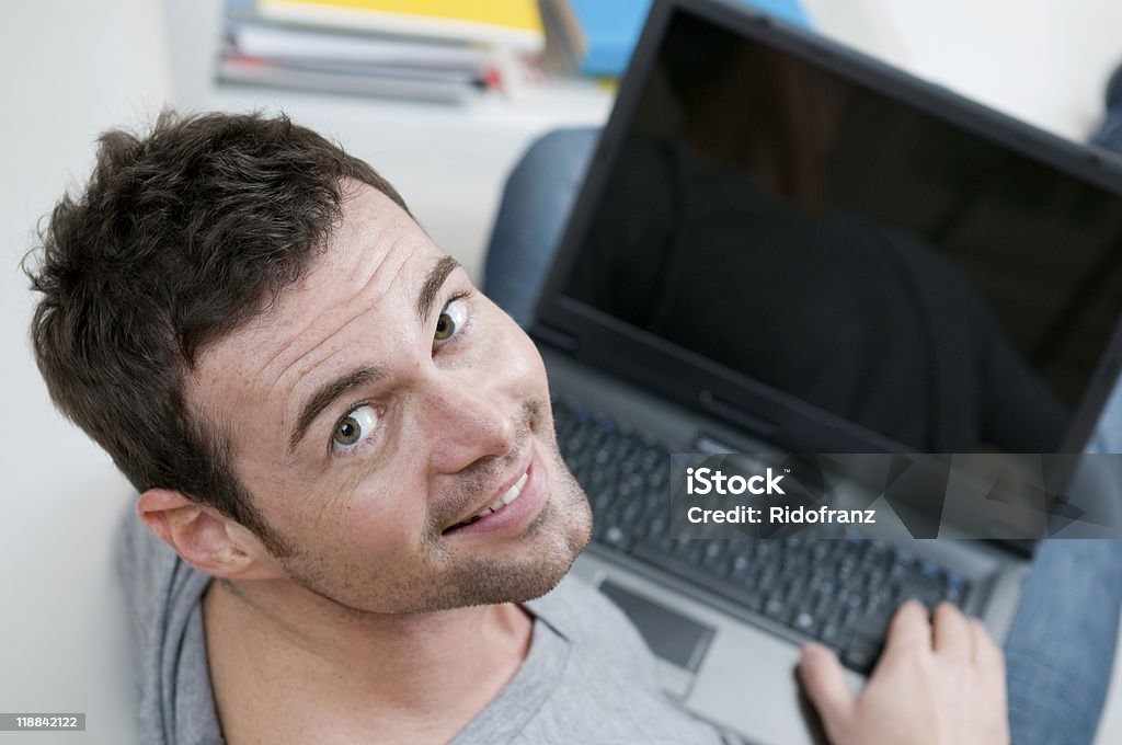 Sorridente uomo casual lavorando sul computer portatile - Foto stock royalty-free di Abbigliamento casual