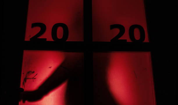 silhouette of a person opening the door handle with date on window with a red strange backlight, destruction of the stereotype happy new year, entering 2020 horror genre silhouette of a person opening the door handle with date on window with a red strange backlight, destruction of the stereotype happy new year, female figure entering 2020 horror genre thriller film genre stock pictures, royalty-free photos & images