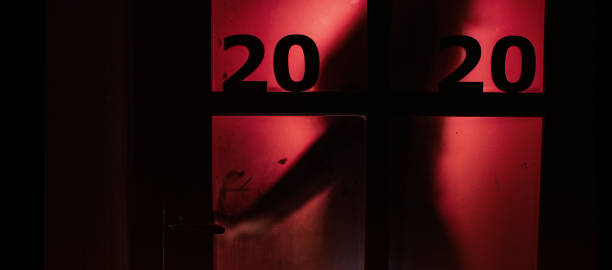 silhouette of a person opening the door handle with date on window with a red strange backlight, destruction of the stereotype happy new year, entering 2020 horror genre silhouette of a person opening the door handle with date on window with a red strange backlight, destruction of the stereotype happy new year, female figure entering 2020 horror genre thriller film genre stock pictures, royalty-free photos & images