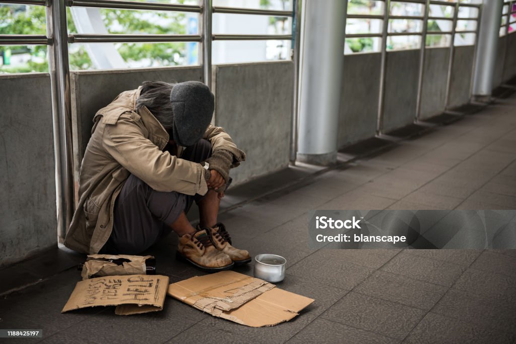 Sad Homeless old man in city Sad Homeless old man or beggar head down and sit on city walk. Poverty with depression feeling in winter. Social issue concept. Homelessness Stock Photo