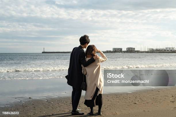 Rear View Of Couple Standing At Beach Stock Photo - Download Image Now - Couple - Relationship, Rear View, Japanese Ethnicity