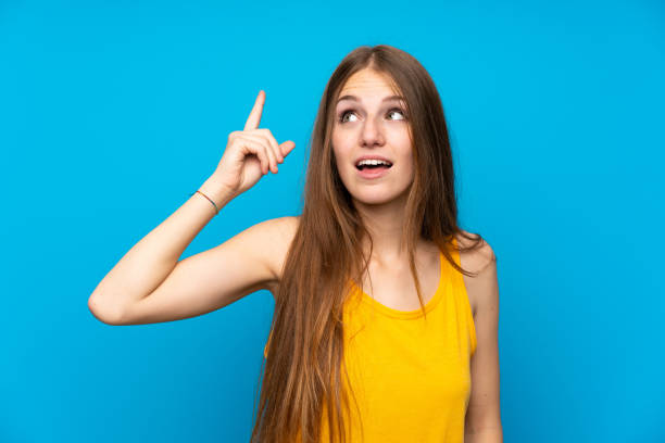 istock Young woman with long hair over isolated blue wall intending to realizes the solution while lifting a finger up 1188426691