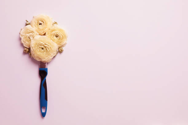 Flowers as paint brush on pink background. Flat lay.