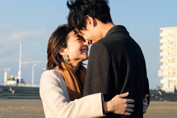 Closeup of young couple embracing at beach Young couple dating at beach in Autumn only japanese stock pictures, royalty-free photos & images
