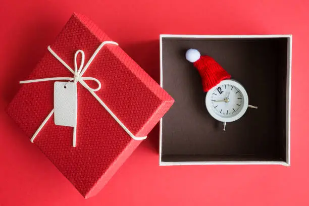 Photo of Analog clock with knitted santa hat in gift box christmas abstract.