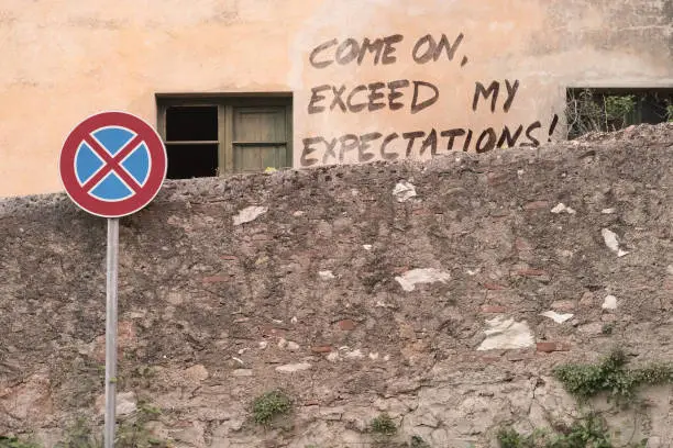 "COME ON EXCEED MY EXPECTATIONS!" is written on an old decrepit wall, with some irony and sarcasm. *** The text was digitally added and a release is provided ***