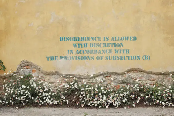 “Disobedience is allowed with discretion in accordance with the provisions of subsection (b)” is written on this wall. *** The text was digitally superimposed and a release is provided ***