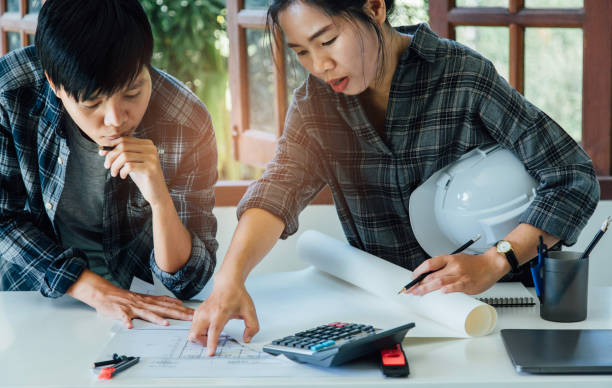 istock Asian couple architect Discussing working and brainstorming.meeting in office. Teamwork of young people colleague talking and presentation planning project on a blueprint 1188429816