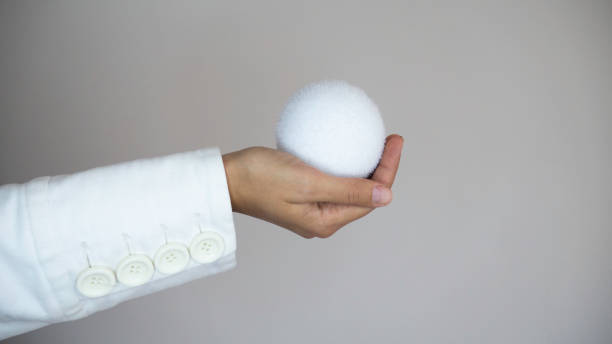istock The woman's hand in a white coat with white buttons holds a white snowball. Negative space. 1188431830