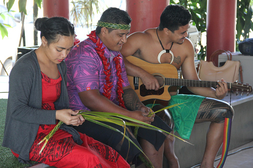 Samoan villager singing their traditional song while weaving the headgear with palm leaves at Samoan cultural village.