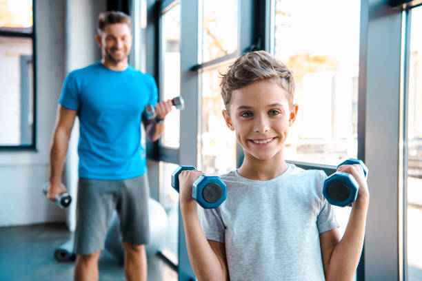 istock selective focus cute kid exercising with dumbbells near father 1188433103