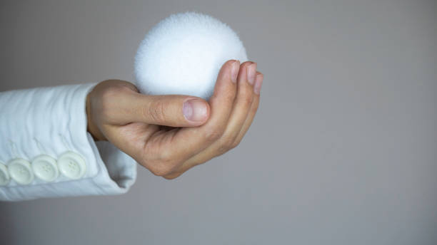 istock The right woman's hand in a white coat with white buttons holds a white snowball. Copy space for advertising. 1188433170