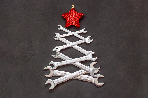 Christmas tree made of tools. Wrenches spanners on black background. Industrial greeting card and happy new year creative concept.