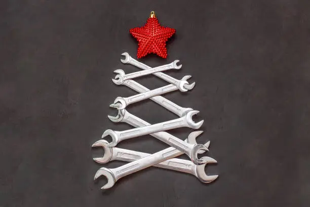 Photo of Christmas tree made of tools. Wrenches spanners on black background. Industrial greeting card and happy new year creative concept.