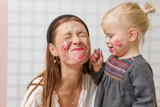 мама и ребенок, играющие с краской для лица, концепция семейного времени - воспитатель стоковые фото и изображения
