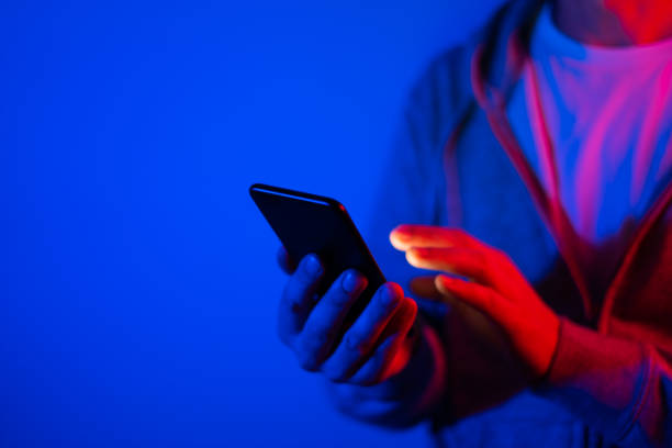istock Male hand with smartphone. Finger typing on screen. Neon light 1188434964