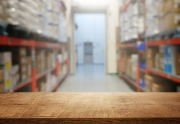 istock warehouse background, wooden empty table and blurred storage shelfs. Ready for mock up or product display industry 1188435487