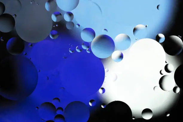 Colorful abstract background. Blue purple white black circles and oil bubbles in the water. Close up. Macro abstraction. Rainbow oil pattern and texture.
