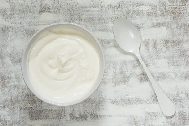 istock Sour cream in white bowl with white spoon on white background 1188438252