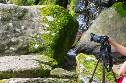 a tripod and camera on rocks of a river