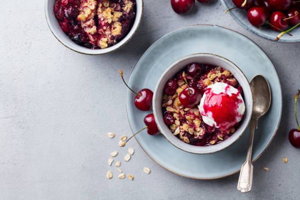 istock Cherry crumble with ice cream in bowl. Grey background. Copy space. Top view. 1188442958