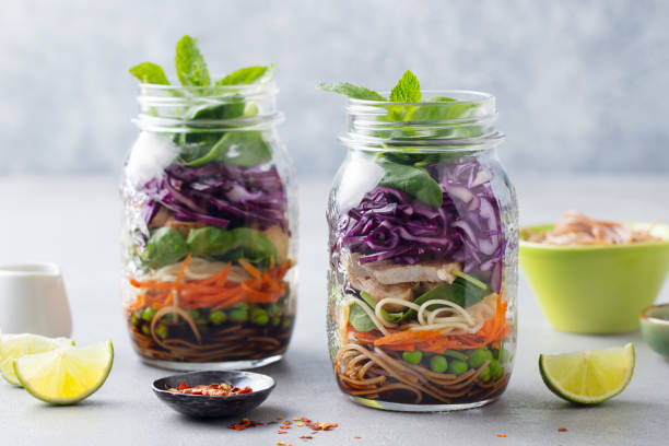 ensalada asiática saludable con fideos, verduras, pollo y tofu en frascos de vidrio. fondo gris. - frasco para conservas fotografías e imágenes de stock