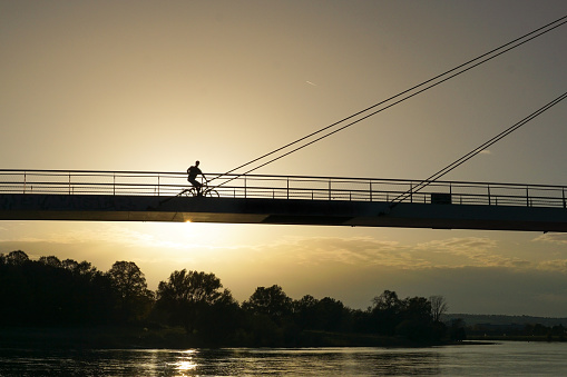 the silhouette of a cyclist on the Elbe Cycle Route passing through Dresden Pieschen at sunset
