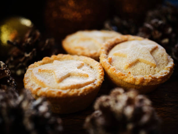 istock Three Mince Pies against dark wood with snow covered pine cones. 1188446436