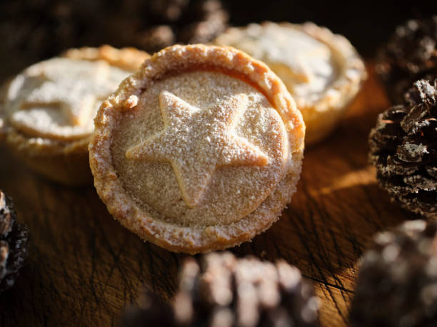istock Three Mince Pies against dark wood with snow covered pine cones. 1188446439