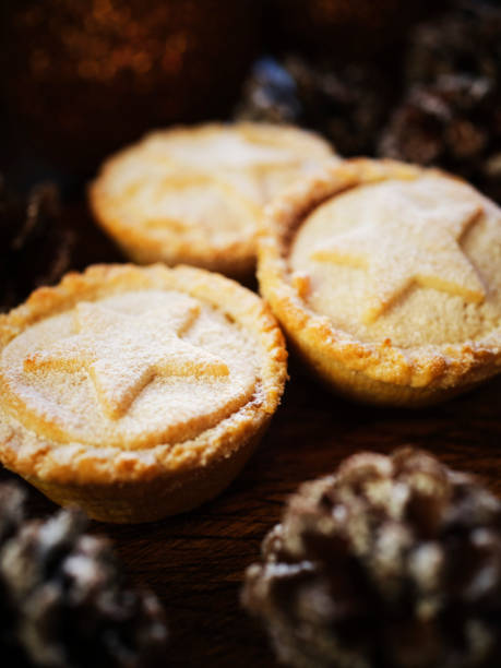 istock Three Mince Pies against dark wood with snow covered pine cones. 1188446458