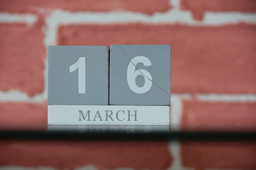 MARCH 16 Against a red brick wall