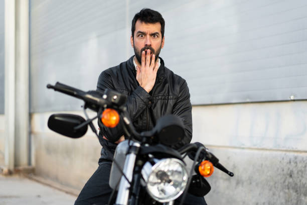 Young man on a motorbike making surprise gesture