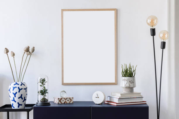 istock Stylish scandinavian interior design with mock up picture frames, navy blue commode, flowers in vase, books and elegant accessories. Modern home decor. Living room. Template Ready to use. 1188452712