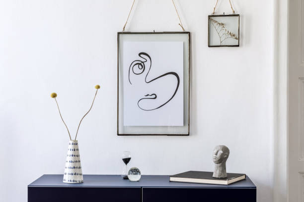 istock Stylish scandinavian interior design with mock up picture frames, navy blue commode, flowers in vase, books and elegant accessories. Modern home decor. Living room. Template Ready to use. 1188452851
