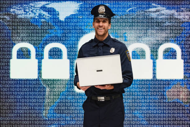 One man only / one person / waist up / front view of young men police force / security staff / computer programmer standing wearing hat / badge who is smiling / happy / cheerful who is working / coding and using laptop / computer / virtual reality / crime / binary code / computer network / computer software / data / encryption / firewall / identity / internet / lock / network security / padlock / password / privacy / security / world map un hombre sólo / una persona / cintura para arriba / vista frontal de la policía de los hombres jóvenes / personal de seguridad / programador de computadora de pie con sombrero / insignia que es sonriente / feliz / alegre que está trabajando / codifica