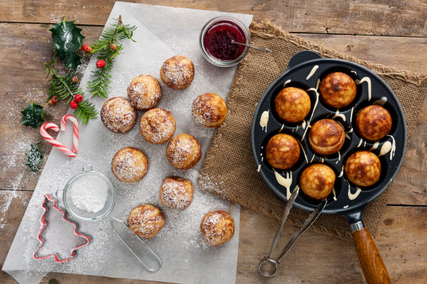 Traditional apple pancakes or Aebleskiver in danish. Traditional apple slices or aebleskiver in danish. Their name does not describe them very well. They are ball-shaped bread dough with a pancake-like texture. Traditionally eaten in the run-up to Christmas they are a Danish “comfort food” to eat in the long winter nights. A piece of apple or prune can be added to the middle of the dough halfway through cooking although this is optional, they are usually eaten with jam or fresh fruit and a dusting of icing sugar. Colour, horizontal with some copy space. danish culture stock pictures, royalty-free photos & images