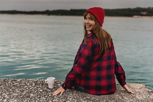 Beautiful woman enjoying her day in the lake with a mug of hot coffee