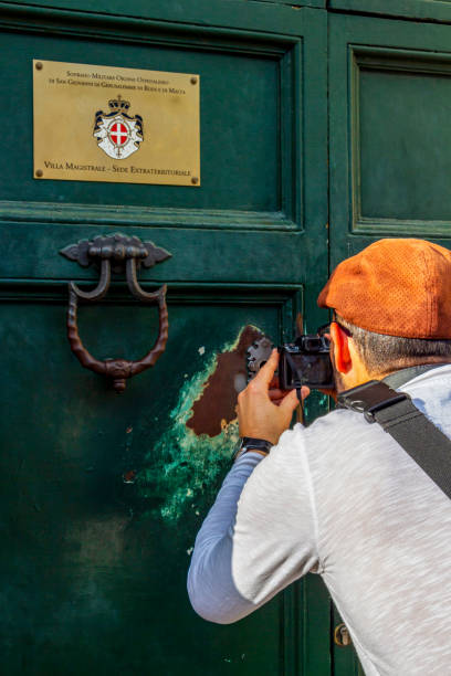 Villa Magistrale, Villa del Priory of Malta in Rome, Italy Rome, Italy - November 24, 2017: Male tourist takes picture of the Aventine Keyhole, Il Buco Della Serratura of Villa Magistrale, Villa del Priorato di Malta knights of malta stock pictures, royalty-free photos & images