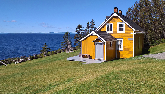 Forillon,Quebec, Canada; September, 6, 2019:  Traditional wooden yellow house of Canada. Views of the St. Lawerence river.
