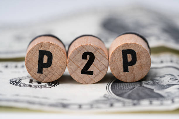 p2p word on wooden blocks over dollar bill - peer to peer imagens e fotografias de stock