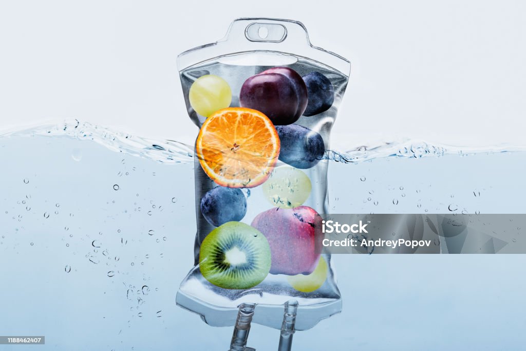 Fruit Slices In Saline Bag Dipped In Water Against Background Close-up Of Various Fruit Slices In Saline Bag Dip In Water Against White Background IV Drip Stock Photo