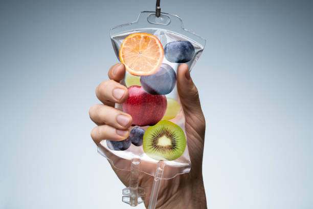 Human Hand Holding Saline Bag With Fruit Slices Over Grey Background Person's Hand Holding Saline Bag Filled With Various Fruit Slices Against Grey Backdrop iv drip photos stock pictures, royalty-free photos & images