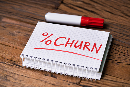 Checkered Notepad With Churn Percent Text Near Red Marker Over Wooden Desk