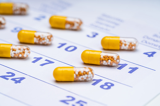 Close-up Of Yellow Transparent Capsules On Calendar Dates