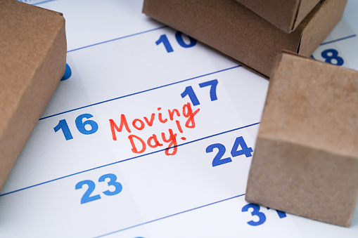 Elevated View Of Moving Day Text On Calendar With Small Cardboard Boxes