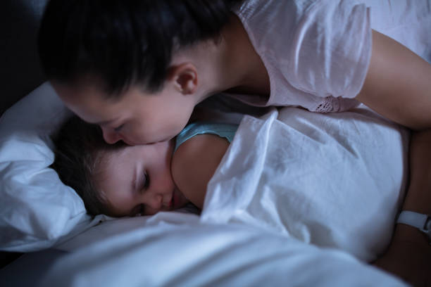 istock Mother Kissing Her Sleeping Daughter On Bed 1188464304