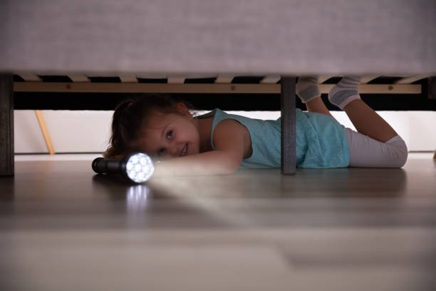 istock Little Girl Looking Under The Bed With Flashlight 1188464352